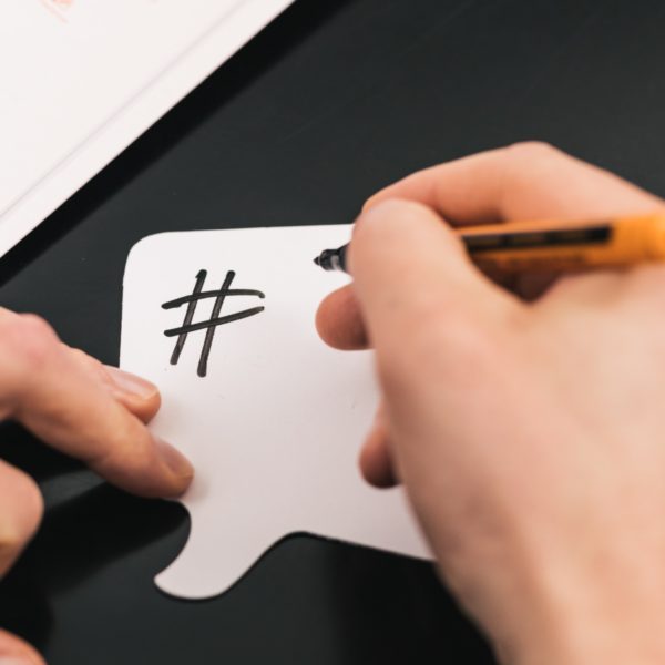 Hände beschriften eine Moderationskarte im Workshop